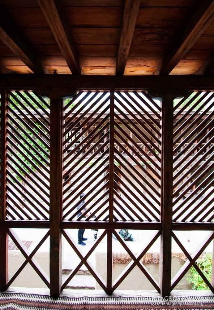 Intricate wooden jali screens filter mountain light into interior spaces.