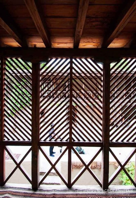 Intricate wooden jali screens filter mountain light into interior spaces.
